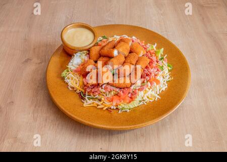 salade avec des doigts de fromage mozzarella hachés, du jambon en dés, du fromage râpé et de la laitue iceberg avec sauce au curry sur une assiette de couleur argile Banque D'Images