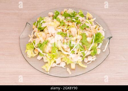 Une généreuse portion de salade César avec des croûtons, du poulet et de la laitue dans une assiette en verre transparent Banque D'Images