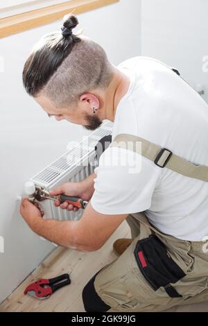 Plomber l'installation d'un nouveau radiateur de chauffage central à eau chaude en acier Banque D'Images