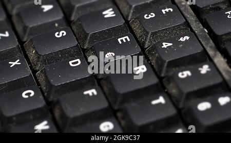 Détail des boutons d'un clavier informatique européen en plastique noir poussiéreux. Technologie et ordinateurs. Poussière et saleté Banque D'Images