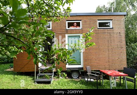 07 septembre 2021, Hessen, Schöneck-Kilianstädten: Uwe Christof regarde par une fenêtre de sa petite maison, qui est située dans son jardin d'allotement. Depuis des années, le spécialiste INFORMATIQUE de la retraite anticipée fait campagne pour ce qu'on appelle les petites maisons, essentiellement transportables qui, malgré leur faible encombrement, sont censées offrir à leurs habitants tout ce dont ils ont besoin pour vivre et peuvent être mis en place partout où cela est permis et les propriétaires aiment cela. À Hesse aussi, cela pourrait se transformer en une forme de vie pour l'avenir. (À dpa 'petites maisons avec un grand avenir? Les petites maisons aussi en demande à Hess Banque D'Images