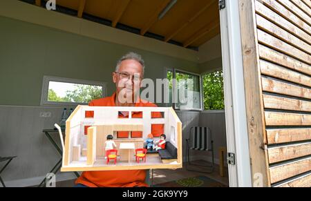 07 septembre 2021, Hessen, Schöneck-Kilianstädten: Uwe Christof tient un modèle pour le design intérieur à la fenêtre de sa petite maison, qui se trouve dans son jardin d'allotement. Depuis des années, le spécialiste INFORMATIQUE de la retraite anticipée fait campagne pour ce qu'on appelle les petites maisons, essentiellement transportables qui, malgré leur faible encombrement, sont censées offrir à leurs habitants tout ce dont ils ont besoin pour vivre et peuvent être mis en place partout où cela est permis et les propriétaires aiment cela. À Hesse aussi, cela pourrait se transformer en une forme de vie pour l'avenir. (À dpa 'petites maisons avec un grand avenir? Petit Hou Banque D'Images