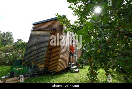 07 septembre 2021, Hessen, Schöneck-Kilianstädten: Uwe Christof se dresse à l'entrée de sa petite maison, qui est située dans son jardin d'allotement. Depuis des années, le spécialiste INFORMATIQUE de la retraite anticipée fait campagne pour ce qu'on appelle les petites maisons, essentiellement transportables qui, malgré leur faible encombrement, sont censées offrir à leurs habitants tout ce dont ils ont besoin pour vivre et peuvent être mis en place partout où cela est permis et les propriétaires aiment cela. À Hesse aussi, cela pourrait se transformer en une forme de vie pour l'avenir. (À dpa 'petites maisons avec un grand avenir? Petites maisons également en demande à Hes Banque D'Images