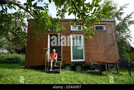 07 septembre 2021, Hessen, Schöneck-Kilianstädten: Uwe Christof est assis à l'entrée de sa petite maison, qui est située dans son jardin d'allotement. Depuis des années, le spécialiste INFORMATIQUE de la retraite anticipée fait campagne pour ce qu'on appelle les petites maisons, essentiellement transportables qui, malgré leur faible encombrement, sont censées offrir à leurs habitants tout ce dont ils ont besoin pour vivre et peuvent être mis en place partout où cela est permis et les propriétaires aiment cela. À Hesse aussi, cela pourrait se transformer en une forme de vie pour l'avenir. (À dpa 'petites maisons avec un grand avenir? Les petites maisons aussi en demande Banque D'Images