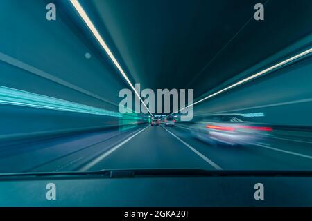 Conduite en tunnel à grande vitesse - concept bleu sarcelle et orange coloré pour courir la nuit dans un tunnel avec effet de flou de mouvement. Banque D'Images