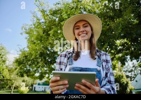 Femme paysanne caucasienne debout à l'extérieur en tapant sur une tablette numérique Banque D'Images