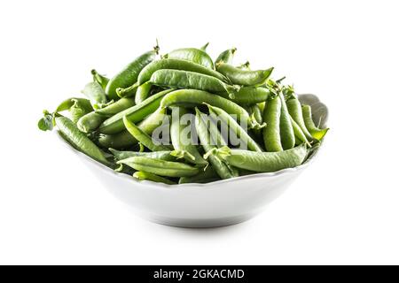 Gousses de pois verts frais dans un bol blanc isolé sur fond blanc. Banque D'Images