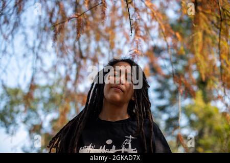 Femme debout sous l'arbre tout en regardant vers le bas l'appareil photo Banque D'Images