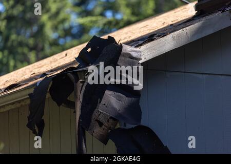 Vieux bardeaux foncés qui pendre du toit en besoin de rénovation Banque D'Images