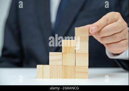 Les mains d'un homme d'affaires qui empilent des blocs de bois. Concept d'entreprise. Banque D'Images