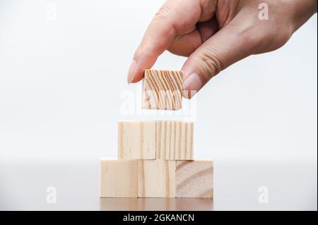 Les mains d'un homme d'affaires qui empilent des blocs de bois. Concept d'entreprise. Banque D'Images