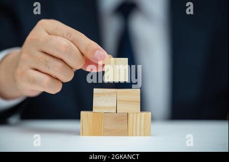 Les mains d'un homme d'affaires qui empilent des blocs de bois. Concept d'entreprise. Banque D'Images