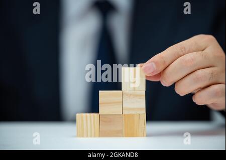 Les mains d'un homme d'affaires qui empilent des blocs de bois. Concept d'entreprise. Banque D'Images