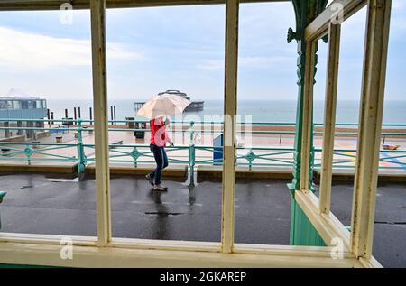 Brighton Royaume-Uni 14 septembre 2021 - une marchette tôt le matin avec un parasol en forte pluie le long de Brighton front de mer avec plus d'un mois de précipitations prévues pour certaines parties de la Grande-Bretagne aujourd'hui : crédit Simon Dack / Alay Live News Banque D'Images