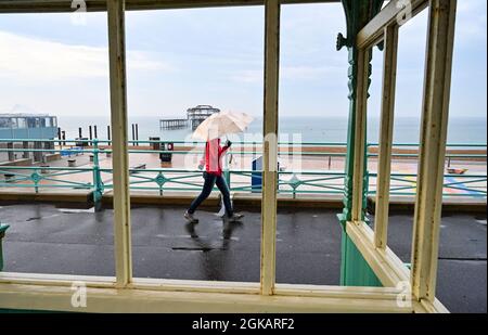 Brighton Royaume-Uni 14 septembre 2021 - une marchette tôt le matin avec un parasol en forte pluie le long de Brighton front de mer avec plus d'un mois de précipitations prévues pour certaines parties de la Grande-Bretagne aujourd'hui : crédit Simon Dack / Alay Live News Banque D'Images