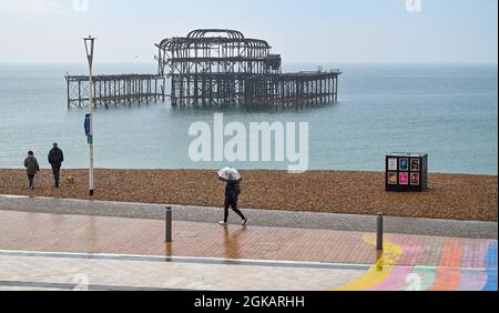 Brighton Royaume-Uni 14 septembre 2021 - un marcheur tôt le matin avec un parapluie sous une forte pluie par la jetée ouest de Brighton avec plus d'un mois de prévisions de précipitations pour certaines parties de la Grande-Bretagne aujourd'hui : crédit Simon Dack / Alamy Live News Banque D'Images