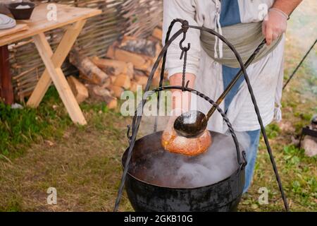 Préparation de la soupe dans un pot suspendu au-dessus du feu ouvert - concept de camping Banque D'Images