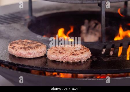 Processus de cuisson des côtelettes pour les hamburgers sur le brazier avec une flamme chaude Banque D'Images