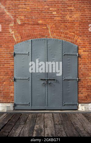 Porte en fer fermée avec cadenas dans un bâtiment historique en brique rouge. Banque D'Images