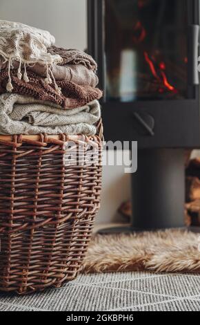 Une pile de vêtements chauds dans un panier en osier une cheminée en fer avec Banque D'Images