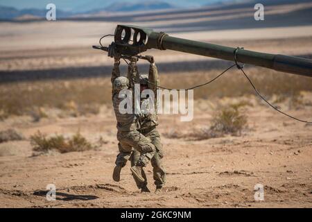 Des soldats d'artillerie de campagne de la Garde nationale de l'Armée de Washington, affectés au 3e Bataillon, 161e Régiment d'infanterie, 'Shark Rifles', 81e équipe de combat de la Brigade Stryker, ajustent le tube de canon d'un Howitzer avant une mission de reconnaissance à la base opérationnelle avancée de la zone de soutien logistique Santa Fe, fort Irwin, Californie, le 10 mars 2021. Les soldats du « fusil noir » passeront environ deux semaines dans la « boîte », une zone d'entraînement massive au sein du Centre national d'entraînement de fort Irwin, où les troupes mettent à l'épreuve leurs tactiques de combat et leur préparation, en vue de leur déploiement en Pologne pour soutenir le multin Banque D'Images