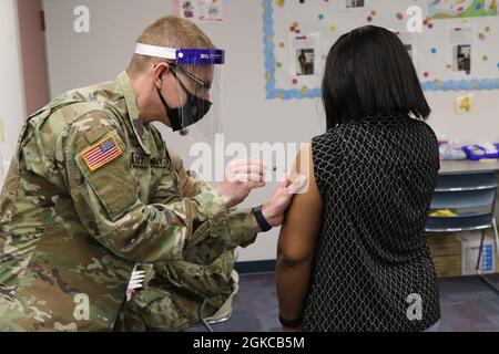 Sergent d'état-major Tyler Lundquist, un medic du site de formation du bataillon médical de la Garde nationale de Pennsylvanie, vaccine un éducateur contre le COVID-19 mar. 11, 2021, à l'unité intermédiaire de la région de la capitale à Enola, en Pennsylvanie. Près de 90 membres de la Garde nationale de Pennsylvanie soutiennent les cliniques de vaccination du COVID-19 pour les enseignants et le personnel scolaire dans sept sites de Pennsylvanie. Banque D'Images