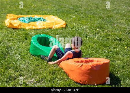 Le bébé joue dans la cour. Vacances d'été pour enfants. Un obstacle sportif pour un pré-chooler. Le garçon saute sur une douce pode sur la pelouse. Banque D'Images