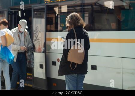 Les gens à l'arrêt de bus. En attente de transport. Les gens se tiennent devant la route en été, attendant le bus. Banque D'Images