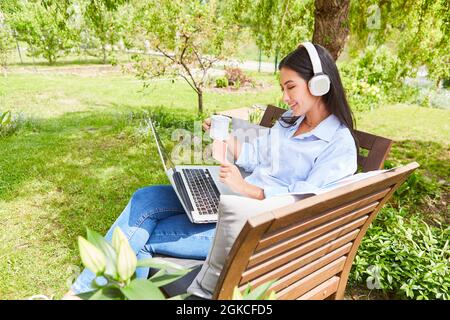 Femme pigiste souriante sur ordinateur portable pendant le chat vidéo dans le jardin en été Banque D'Images