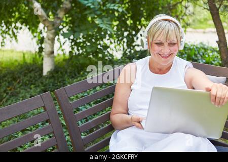 Femme d'affaires souriante sur un ordinateur portable pendant une conversation vidéo dans le jardin en été Banque D'Images