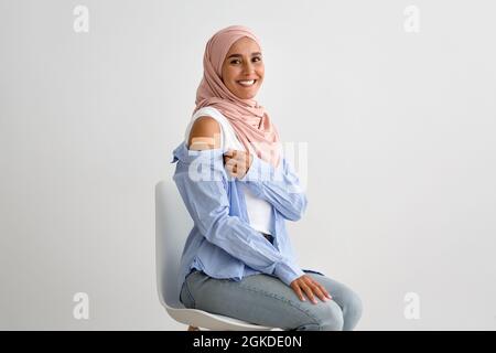 Vaccination Covid-19. Bonne femme musulmane dans le hijab montrant le bras après l'injection du vaccin Banque D'Images