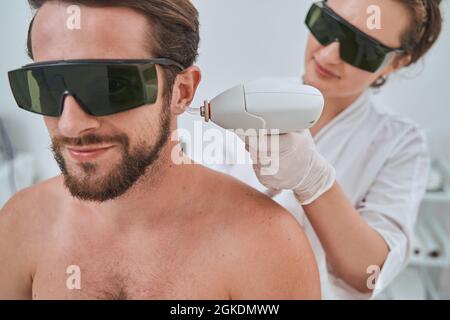 Patient masculin en lunettes de protection soumis à une procédure cosmétique Banque D'Images