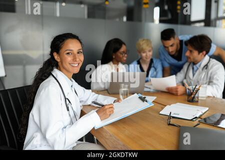 Jeune femme attrayante travaillant sur le rapport pendant la réunion du matin Banque D'Images