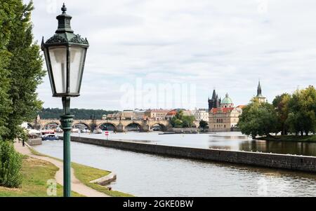 Prague, République tchèque. Vue sur un lampadaire traditionnel au-dessus de la rivière Vlatava, avec le pont Charles visible au loin. Banque D'Images