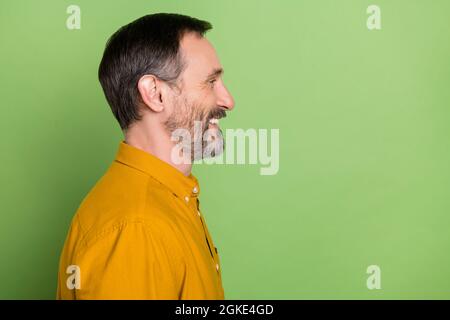 Photo de drôle de charme d'âge gentleman porter l'orange regardant l'espace vide souriant isolé couleur verte arrière-plan Banque D'Images