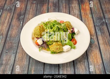 Salade guacamole d'avocat, pousses de laitue, laitue d'agneau, fromage feta, tomates cerises et assiette ronde blanche Banque D'Images