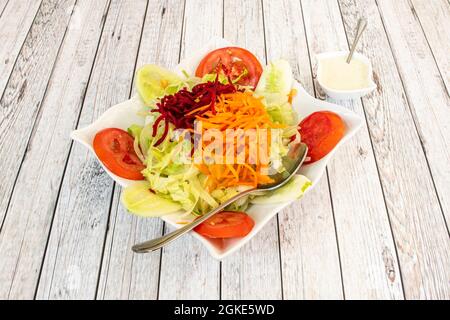 Salade de légumes avec carottes râpées, betteraves rouges, tranches de cornichon, tomates et laitue dans un bol blanc Banque D'Images