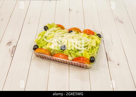 Salade mixte simple avec laitue, tomate, oignon et olives noires présentées dans un récipient de livraison à domicile Banque D'Images