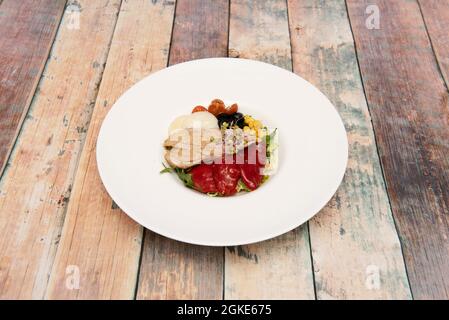 Salade d'arugula avec pousses de haricots, poivrons piquillo en conserve, poitrine de thon, tomates cerises, maïs doux, olives noires sur une élégante assiette blanche Banque D'Images