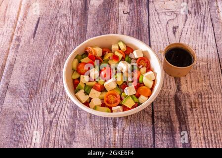 Salade grecque avec tous les ingrédients coupés en dés. Avocat, concombres, poivrons verts et rouges, fromage feta et tomates cerises avec vinaigrette balsamique Banque D'Images