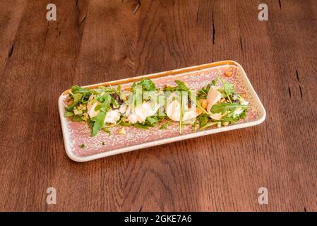 salade de burrata hachée avec noix et arugula sur un plateau et une table en bois Banque D'Images