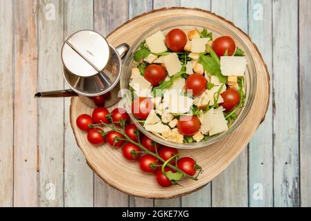 Bol en verre avec salade italienne à l'arugula, tranches de parmesan, tomates cerises à l'intérieur et à l'extérieur du bol, base à l'arugula et croûtons avec des poli espagnols Banque D'Images