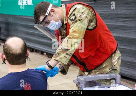 Caporal de l'armée américaine Tydeus Crouse, originaire de Brooklyn, Michigan, et médaillé de combat avec la 2e Brigade combat Team, 101e Airborne Division (Air Assault), administre un vaccin au Wolstein Community Vaccination Centre, à Cleveland, le 28 mars 2021. En tant que fan de l'Université du Michigan, Crouse ne laisse pas le fait qu'il soit en Ohio l'empêcher de faire de son mieux. « même si la majorité des membres de la communauté sont fans de l’État de l’Ohio, il est très agréable de faire des dons à la communauté afin que nous puissions commencer à nous déplacer au-delà de cette pandémie », a-t-il déclaré. Crouse a décidé de rejoindre l'Armée après que l'école secondaire ait continué la famille Banque D'Images