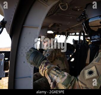 Sergent d'état-major Kevin Novak, UH-60 instructeur de normalisation Black Hawk, regarde l'Adjudant-chef 3 Jennifer Collins, pilote UH-60, tirer la mitrailleuse M240H hors d'un UH-60M Black Hawk lors de la familiarisation avec le feu au sol à fort Sill, Oklahoma, le 24 mars 2021. Novak et Collins sont tous deux avec la Compagnie C, 1er Bataillon d'hélicoptères d'assaut, 140e Aviation Regiment, Garde nationale de Washington. Banque D'Images