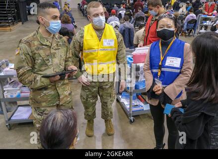 Armée américaine 1er lieutenant Jacob Zortz, centre, originaire de Pittsburg, Kansas, et infirmière autorisée de l'hôpital communautaire de fort Belvoir, et de la CPS. Carlos Lopez, originaire d'Ashtabula, en Ohio, et mécanicien de véhicules de la 145e Brigade d'armure de la Garde nationale de l'Ohio, répond aux questions de santé d'un membre de la communauté tout en étant aidé par Chan Li, un interprète de Vocalink Global, au Wolstein Community vaccine Centre, géré par l'État et soutenu par le gouvernement fédéral, à Cleveland, le 29 mars 2021. Zortz a déclaré qu'il avait choisi la médecine de l'Armée pour avoir un impact positif et qu'il est fier d'avoir l'occasion de servir le peuple américain. U.S. Nort Banque D'Images