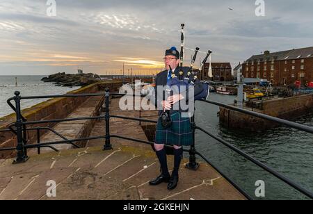 Piper joue des cornemuses à l'aube pour commémorer la St Valery Day (soldats écossais capturés dans la deuxième Guerre mondiale), port de North Berwick, East Lothian, Écosse, Royaume-Uni Banque D'Images