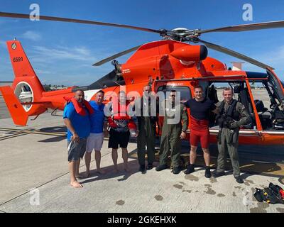 Un équipage d'hélicoptère Dolphin de la station aérienne de la Garde côtière Miami MH-65 prend une photo avec les trois hommes qu'ils ont mis en déroute à environ 16 miles à l'ouest de Bimini, Bahamas, le 31 mars 2021. Le bateau coulait rapidement et les gens sauvent dans l'eau et le nageur les a hissés en toute sécurité sans problème médical. Banque D'Images