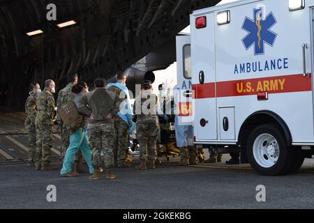 Un patient COVID-19 qui était soigné au centre médical de l'armée de Madigan est chargé sur un C-17 Globemaster III par une équipe d'évacuation aéromédicale du 775e vol d'évacuation aéromédicale expéditionnaire de la base aérienne de Travis, en Californie, Et d'autres professionnels de la santé de Madigan, à la base conjointe Lewis-McChord, Washington, le 31 mars 2021. Le patient était en détresse respiratoire grave et était relié à un système d'oxygénation extracorporelle sur membrane (EMCO), qui aide le corps à respirer. Banque D'Images