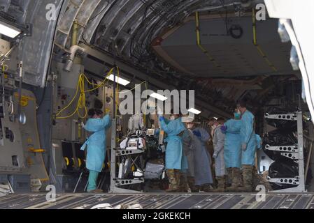 Un patient COVID-19 qui était soigné au centre médical de l'armée de Madigan, est chargé sur un C-17 Globemaster III par une équipe d'évacuation aéromédicale du 775e vol d'évacuation aéromédicale expéditionnaire de la base aérienne de Travis, en Californie, Et d'autres professionnels de la santé de Madigan, à la base conjointe Lewis-McChord, Washington, le 31 mars 2021. Le patient était en détresse respiratoire grave et était relié à un système d'oxygénation extracorporelle sur membrane (EMCO), qui aide le corps à respirer. Banque D'Images