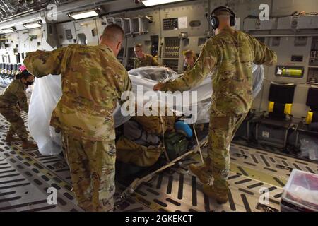 Les aviateurs de la U.S. Air Force du 775e vol d'évacuation aéromédicale expéditionnaire de la base aérienne de Travis, Californie, couvrent leurs bagages et leur équipement avec une bâche en plastique à bord d'un C-17 Globemaster III sur la base conjointe Lewis-McChord, Washington, le 31 mars 2021. Ils ont couvert leur équipement et leurs bagages avec du plastique en préparation pour un patient COVID-19 qui était transporté au centre médical de l'armée de San Antonio au Texas. Banque D'Images